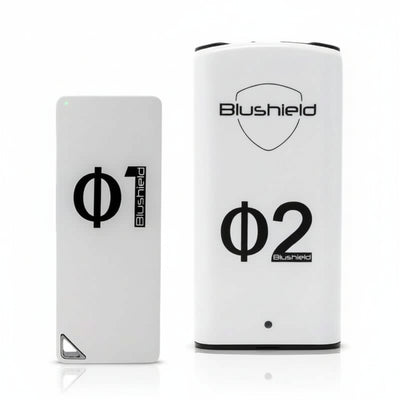 two white devices look like cell phones for EMF protection, one says Φ1 Blushield, the other says Blushield Φ2