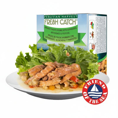 Peruvian Harvest Fresh Catch smoked paché chunks with asparagus, artichokes, and peppers on a plate with a green leafy garnish.